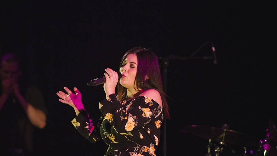 Une jeune femme chante sur une scène