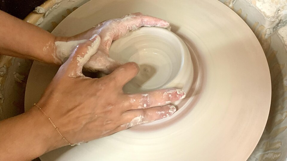 Les mains de Marie-Paul Meideros en train de former une pièce de poterie. 