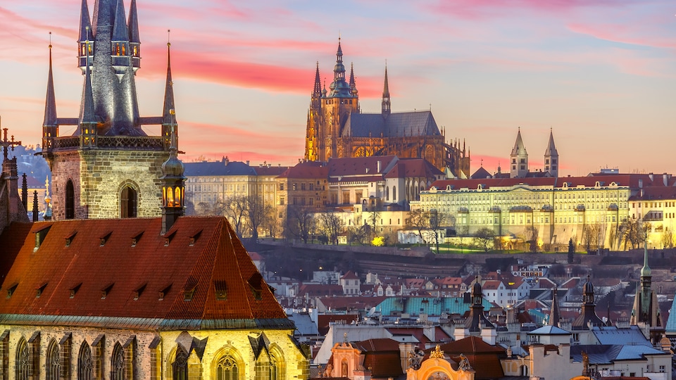 Vue aérienne de la ville de Prague avec la lumière chaude d'un coucher de soleil. On voit une église médiévale en avant plan.