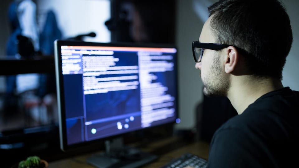 Un homme portant des lunettes utilise un ordinateur. 