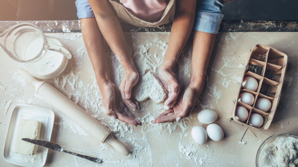Deux personnes confectionnent une patisserie en forme de coeur