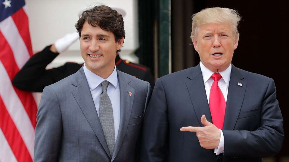 Le président Trump pointe Justin Trudeau du doigt alors que les deux hommes marchent côte à côte.