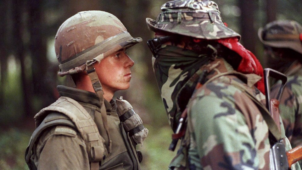 Un soldat de l'Armée canadienne et un Warrior se font face.