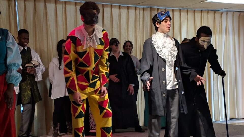 Des adolescents costumés et portant des masques au cours d'une pièce de théâtre.