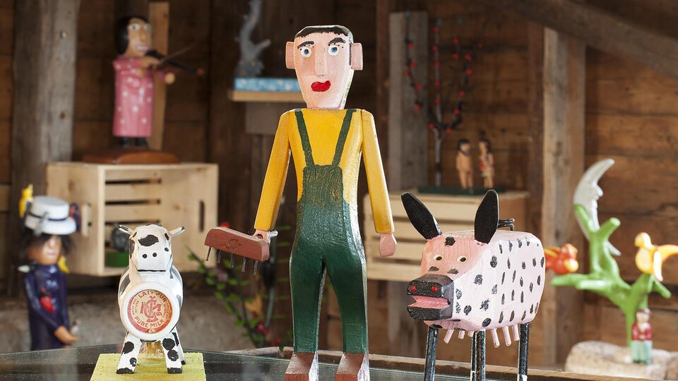 De sculptures d'art populaire : une petite vache, un personnage avec une salopette et un cochon rose avec des points noirs.