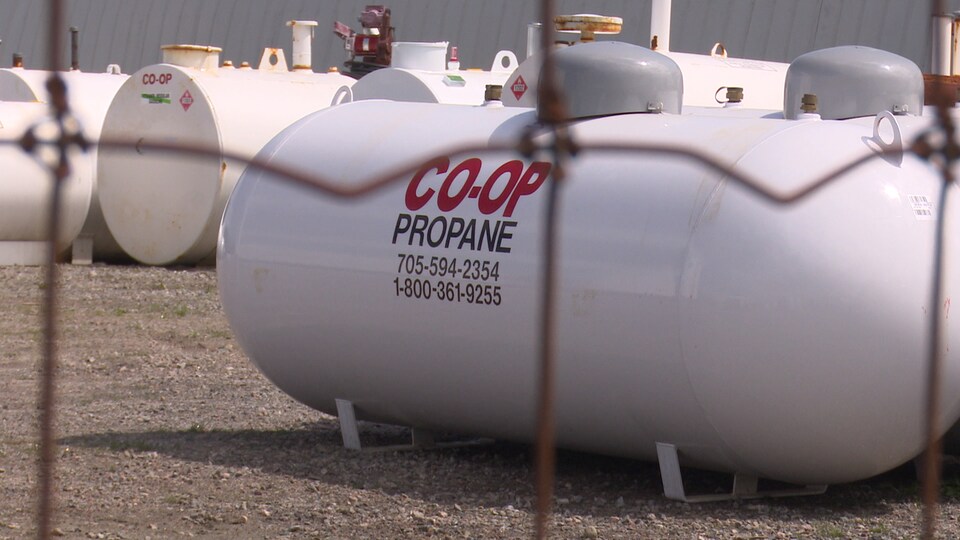 Des réservoirs de propane entreposés derrière un grillage.