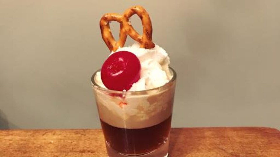 Un petit verre avec de l'alcool et de la crème fouettée sur le dessus.