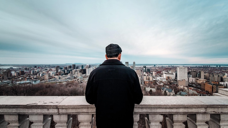 Un homme regarde en direction du centre-ville de Montréal depuis le belvédère Kondiaronk, sur le mont Royal. 