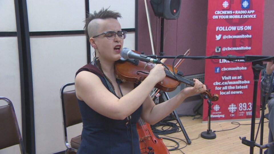 Une musicienne avec les yeux fermés chante en jouant le violon.