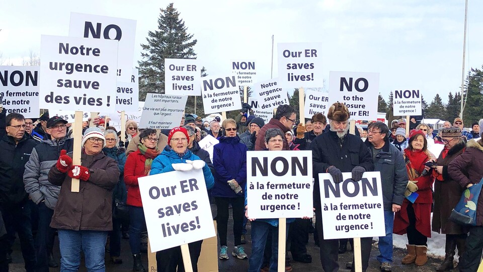 Groupe de personnes brandissant des pancartes sur lesquelles on peut lire «Non à la fermeture de notre urgence!»