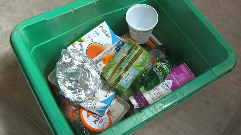 Une boîte verte contenant divers emballages recyclables.