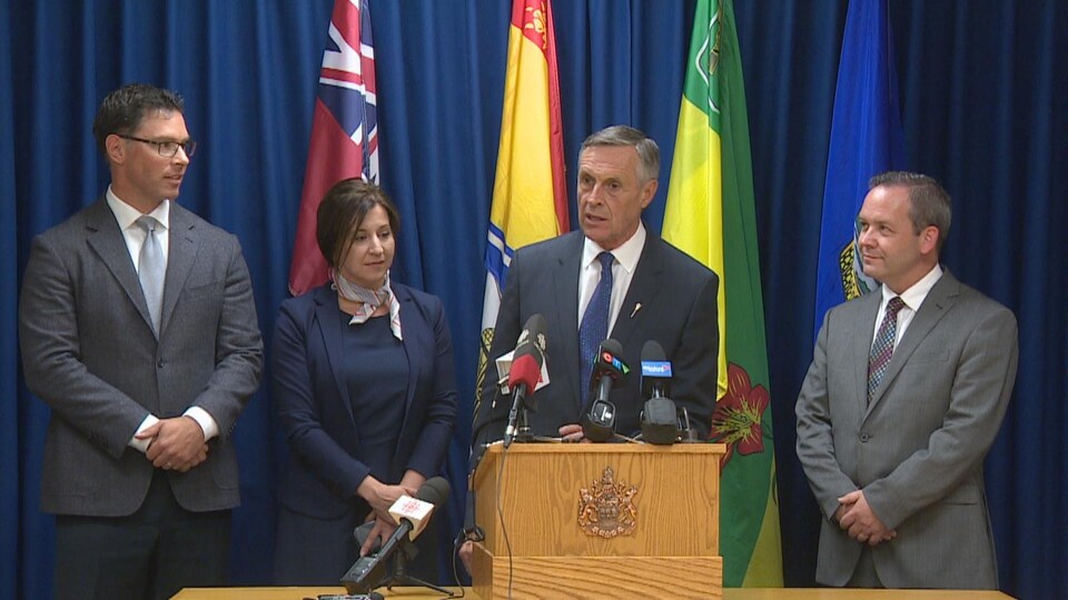 Les quatres ministres à un podium en point de presse.