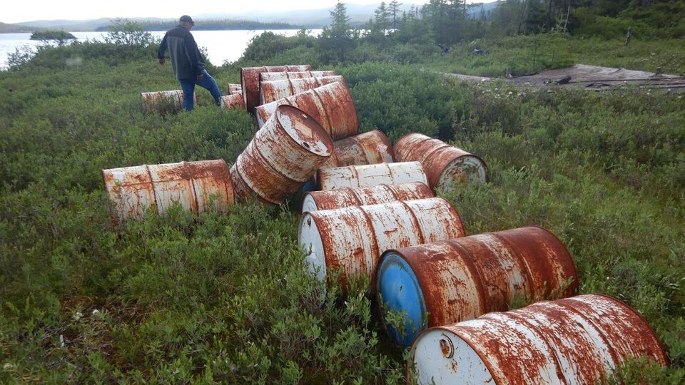 Des bidons de diesels jonchent le rivage d'une rivière.
