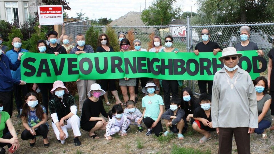 Des personnes tiennent une bannière avec les mots: sauvez notre quartier.