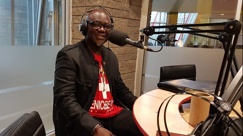écrivain black, chauve et à lunettes dans un studio de radio.