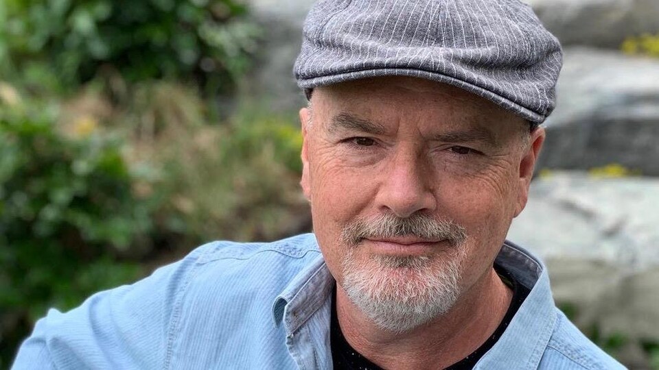 Le musicien Robert Walsh avec sa guitare dans un jardin