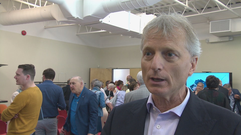 Roger Melanson devant une salle remplie de gens.