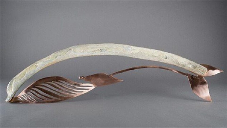 Un os de baleine soutenu d'une sculpture en cuivre.