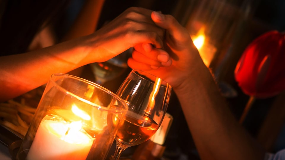 Un couple se tient la main lors d'un souper aux chandelles.