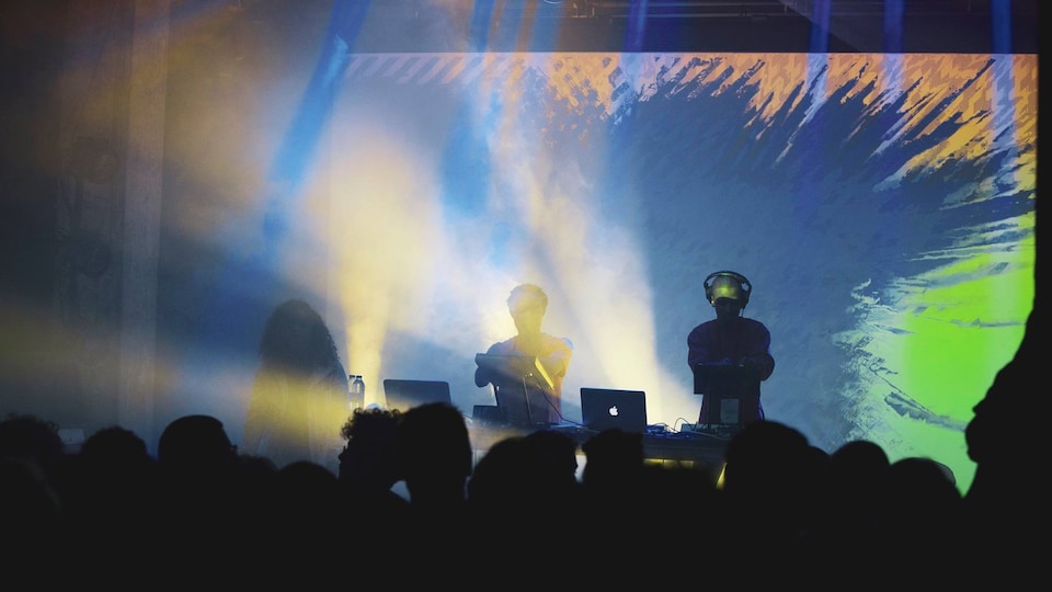 Des DJS performent devant une projection lumineuse colorée psychédélique
