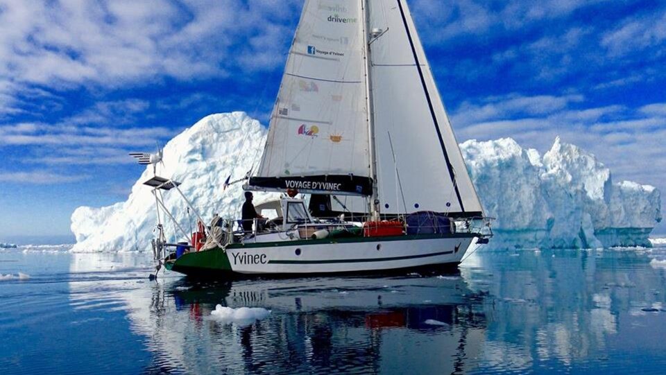 Un bateau à voile approche un iceberg.