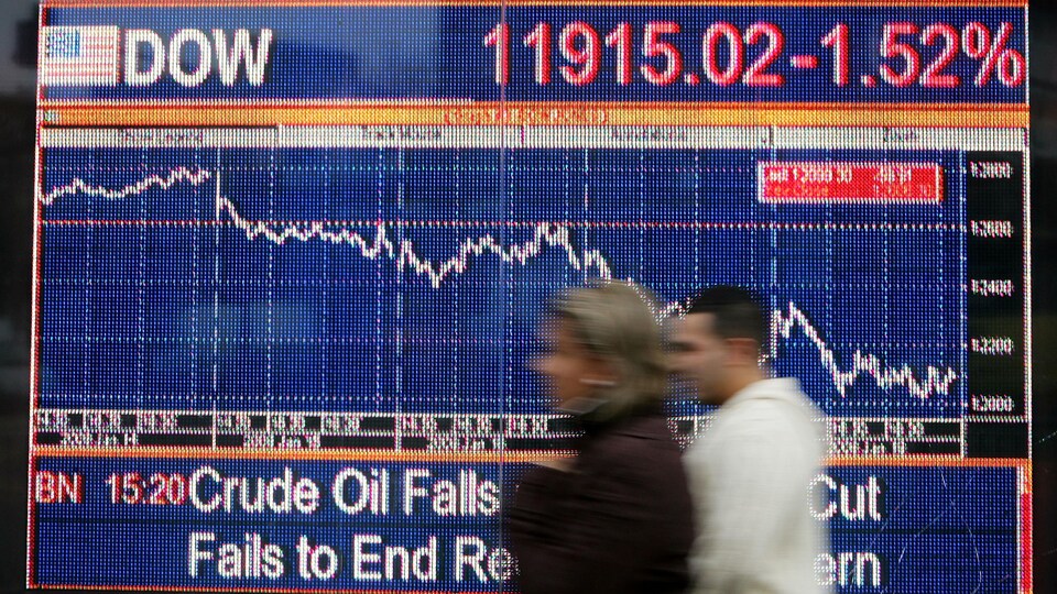 Des passants marchent devant un écran affichant l'indice FTSE, en janvier 2008.