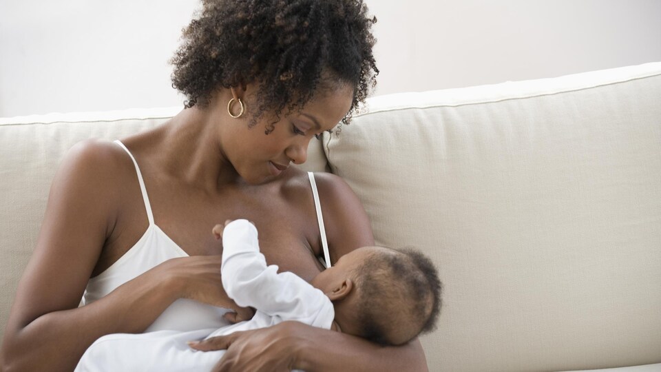 Une mère allaite son enfant sur un sofa.