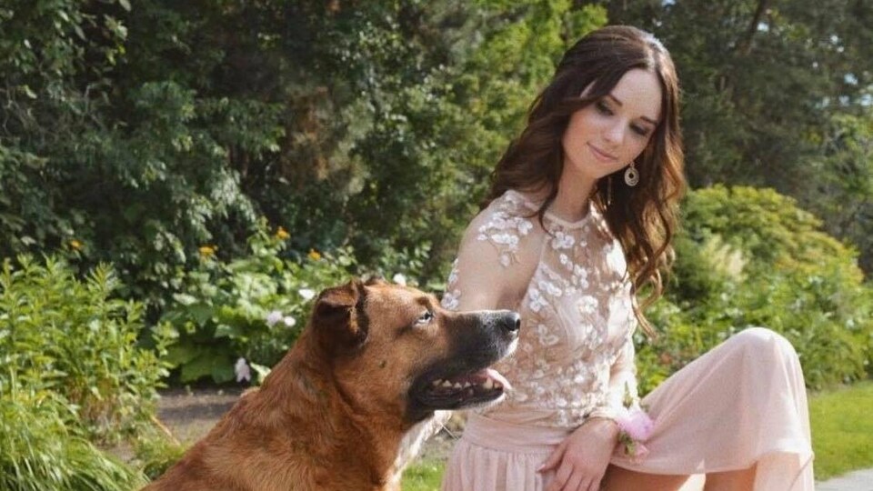 Une jeune femme en robe de bal qui est avec son chien.