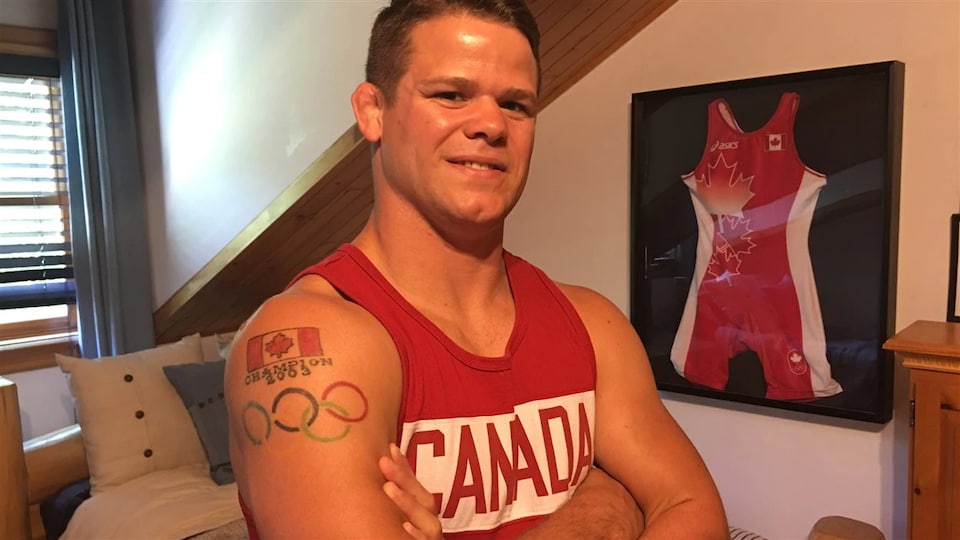 Un jeune lutteur qui pose devant son maillot olympique.