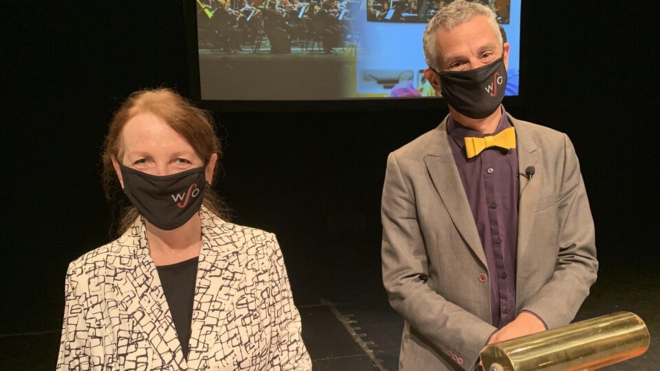 Une femme et un homme portant des masques sont debout devant un podium