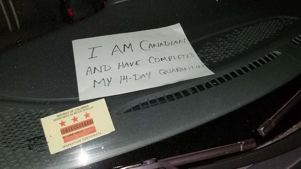 Affiche avec l'inscription «I am Canadian and have completed the 14 day quarantine» à l'intérieur d'une voiture.