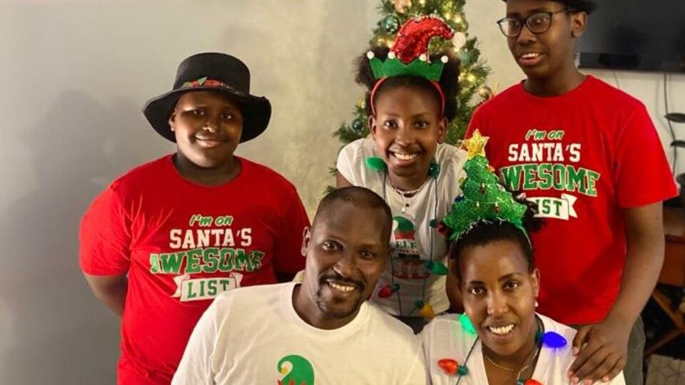 Thérence Maxime Ntunga et sa famille posent devant un arbre de Noël.
