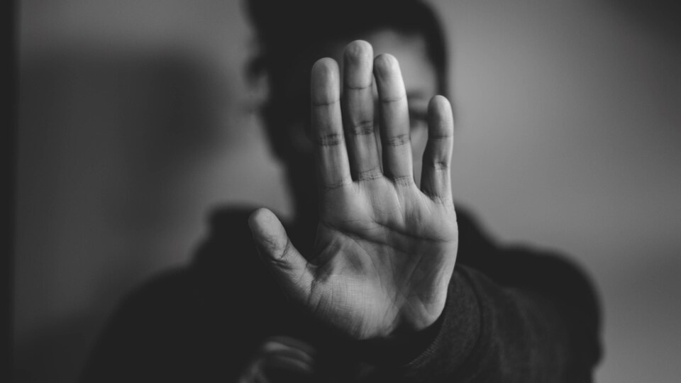 Une femme se défend, en montrant la main en signe «d'arrêt».