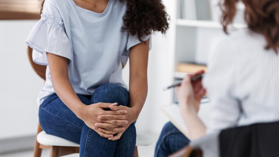 Plan cadré sans montrer les visages de deux femmes assises l'une en face de l'autre.