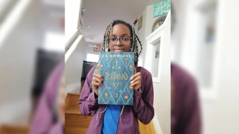 La jeune fille tient un livre dans une maison.