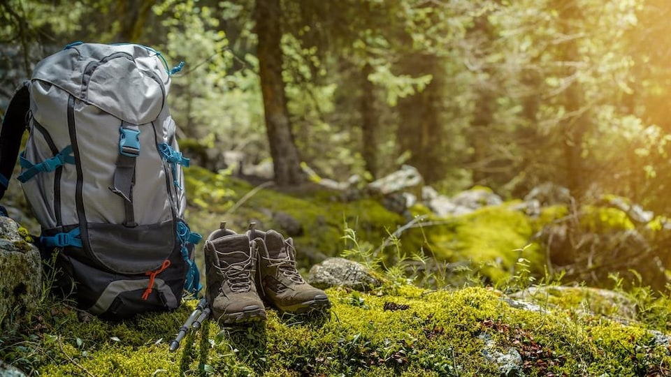 Des bottines et un sac à dos de randonneur dans une clairière en pleine forêt.