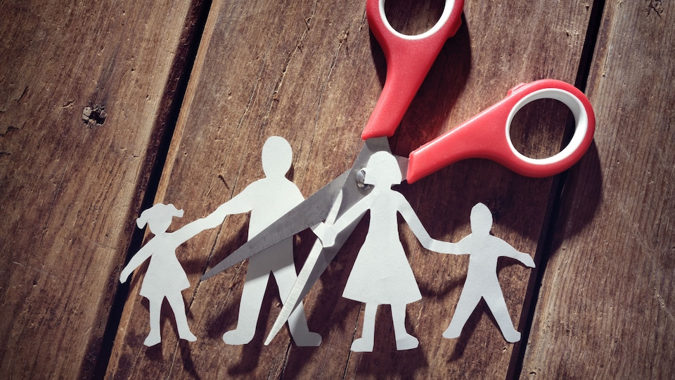L'image d'une famille en papier, découpée par une paire de ciseaux.
