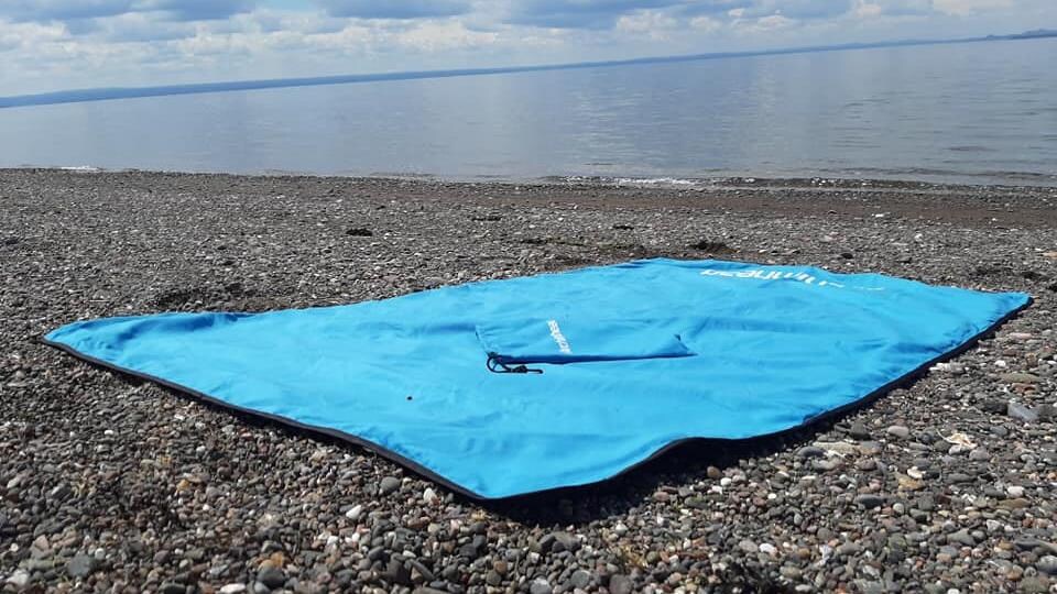 La serviette est étendue sur une plage de galets.