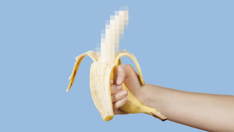 Une personne tient dans sa main une banane dont la moitié épluchée est floutée. 