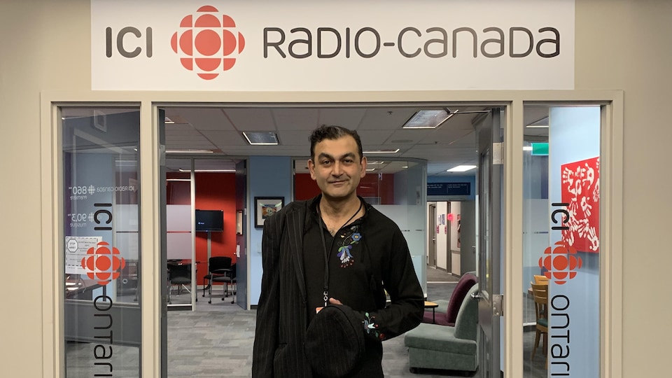 Shamez Amlani se tient debout devant l'enseigne de Radio-Canada.