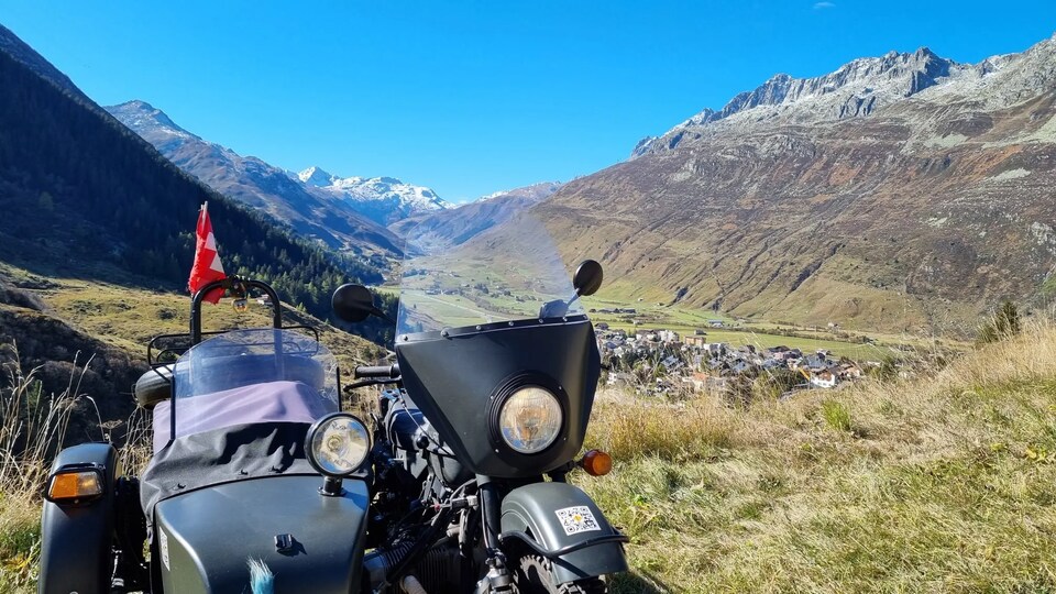 Une moto avec nacelle latérale entourée de montagnes. 