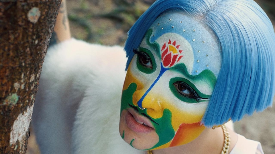 Plan rapproché du visage d'une femme portant un maquillage coloré et arborant une chevelure bleu clair.