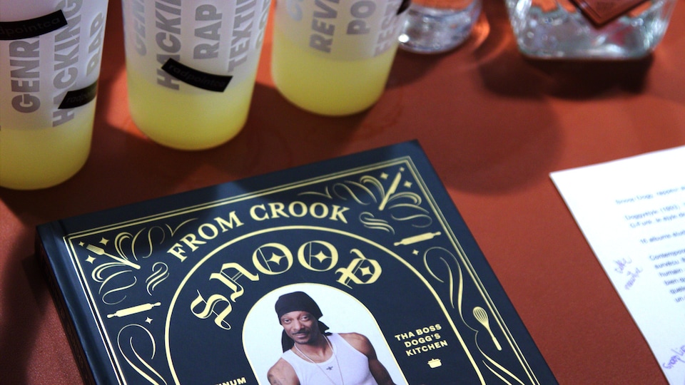 Sur une table, trois verres de plastique, deux bouteilles et le livre de Snoop Dogg.