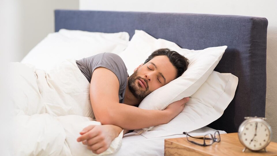 Un homme dort seul dans un lit.