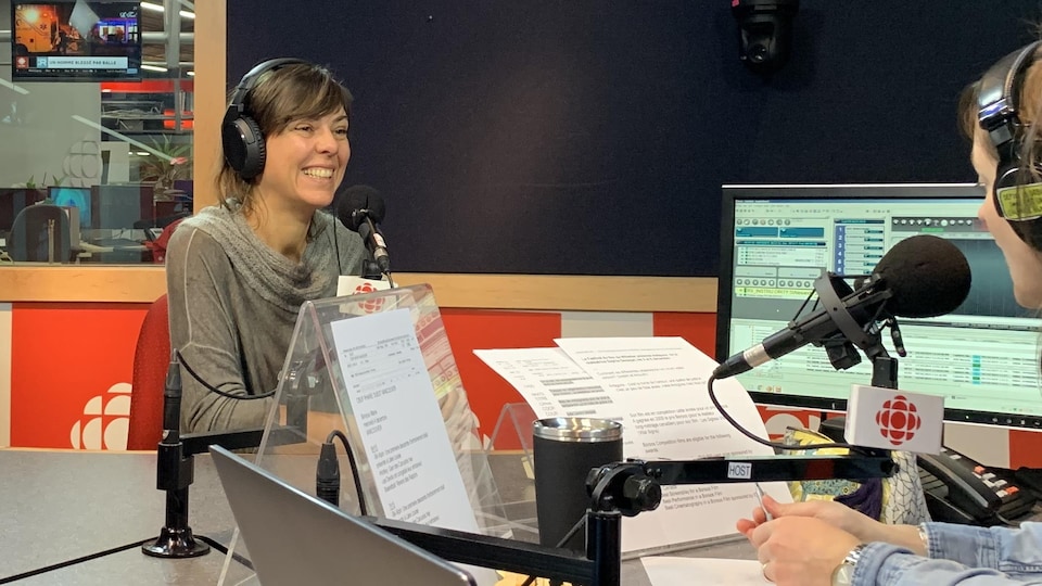 Sophie Deraspe est au micro dans un studio radio. Elle porte des écouteurs et on peut voir un écran d'ordinateur à sa gauche.