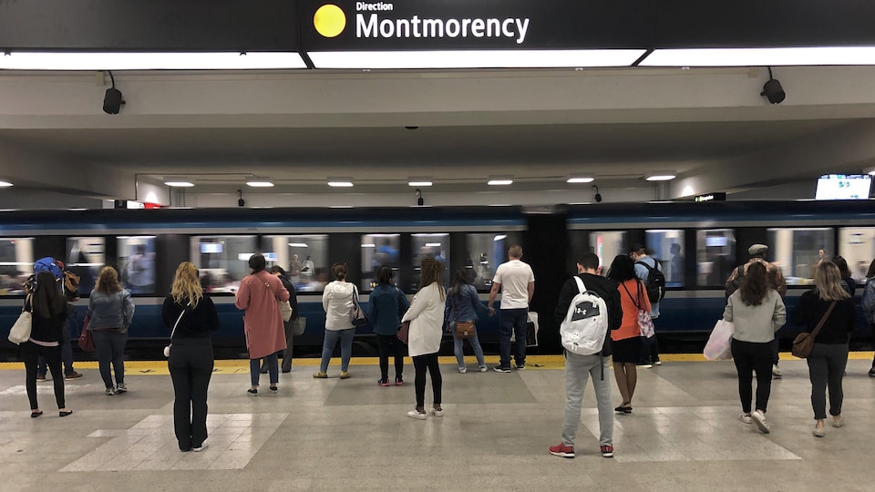 Des usagers attendent sur le quai l'arrivée du métro de la ligne orange en direction Montmorency à la station Berri-UQAM.