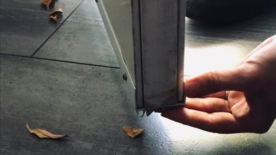 Une main tient le bas d'une porte.