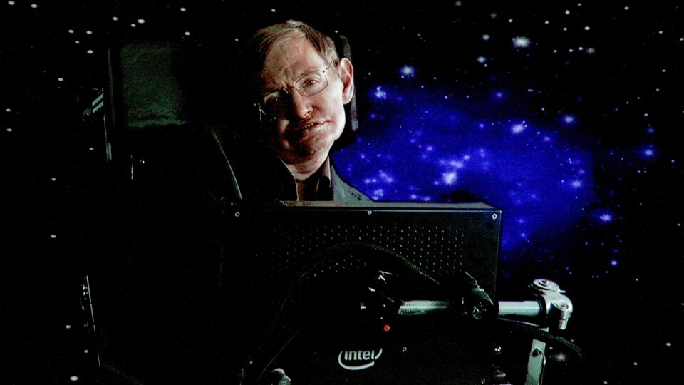 Le scientifique est assis dans sa chaise, avec comme arrière-plan, une image d'un ciel étoilé.