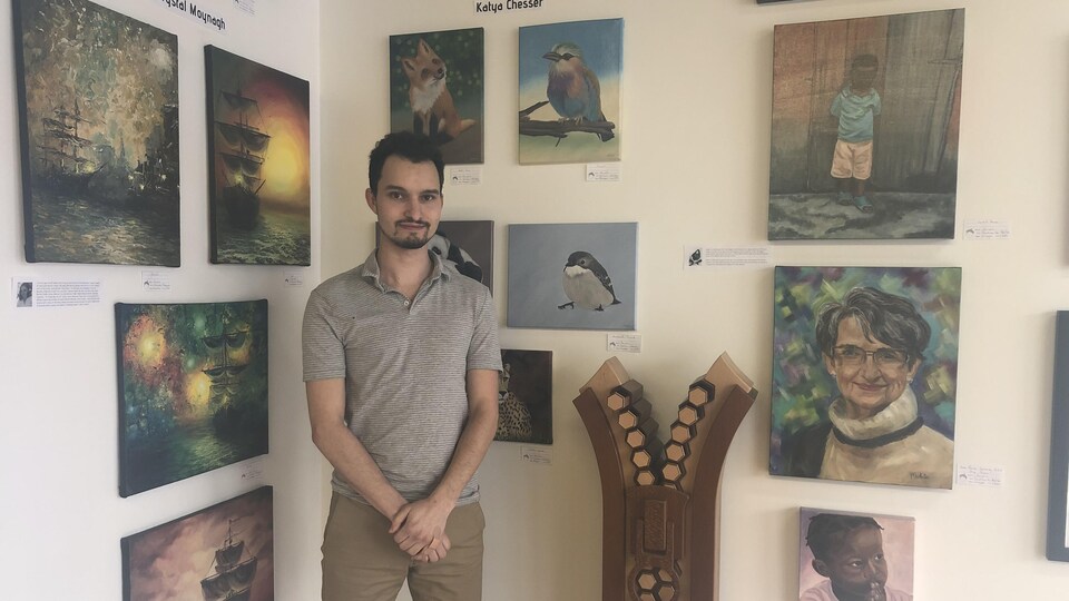 Un homme est debout devant des oeuvres d'art dans une galerie.