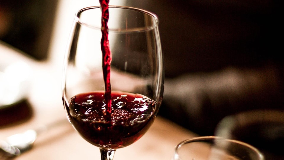 Du vin rouge est versé dans un verre.